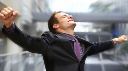 Champion business man standing with fists clenched in victory.